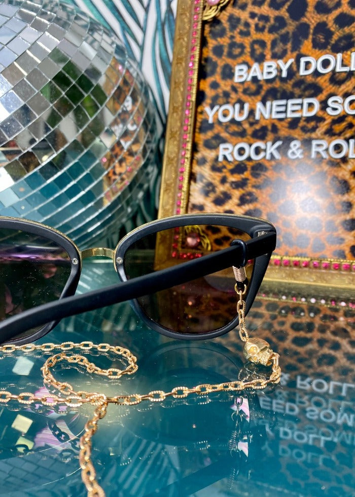 gold skull eyeglass chain on glass surface