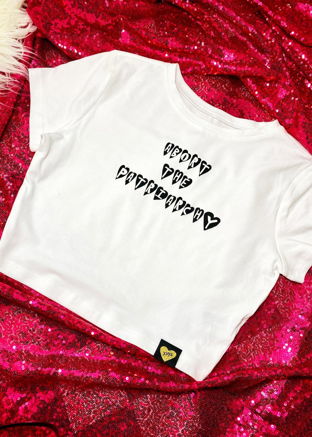 abort the patriarchy crop top on a hot pink sequin background