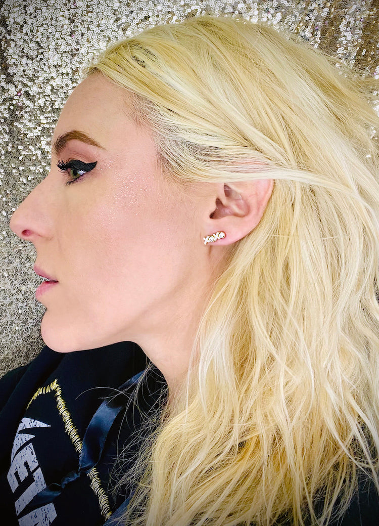 gold and faux diamond earrings in the shape of "xoxo" on model