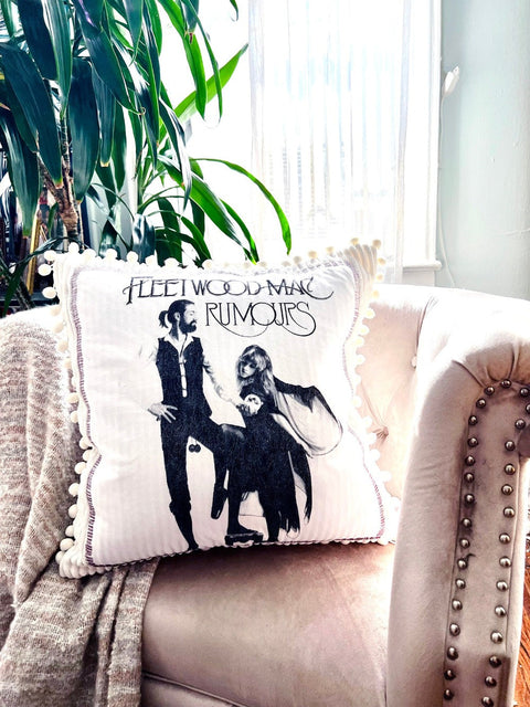 fleetwood mac throw pillow on blush colored chair with plant in the background