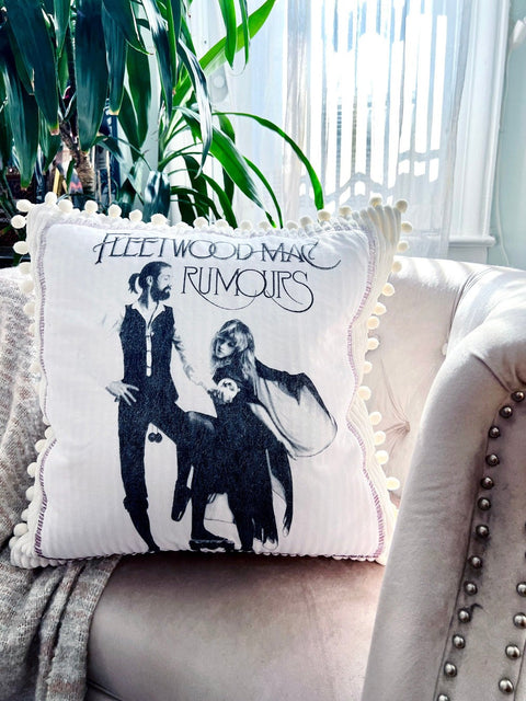 fleetwood mac throw pillow on blush colored chair with plant in the background close up view