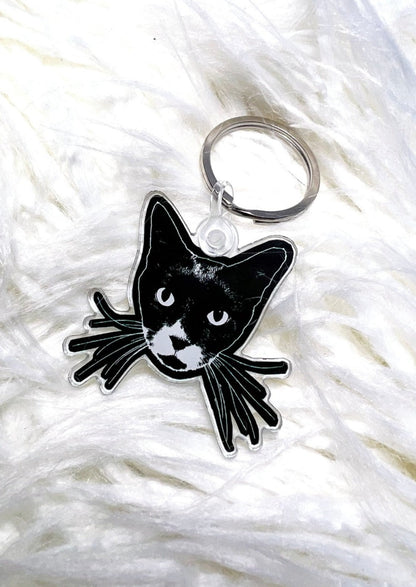 black cat face keychain on a white furry background